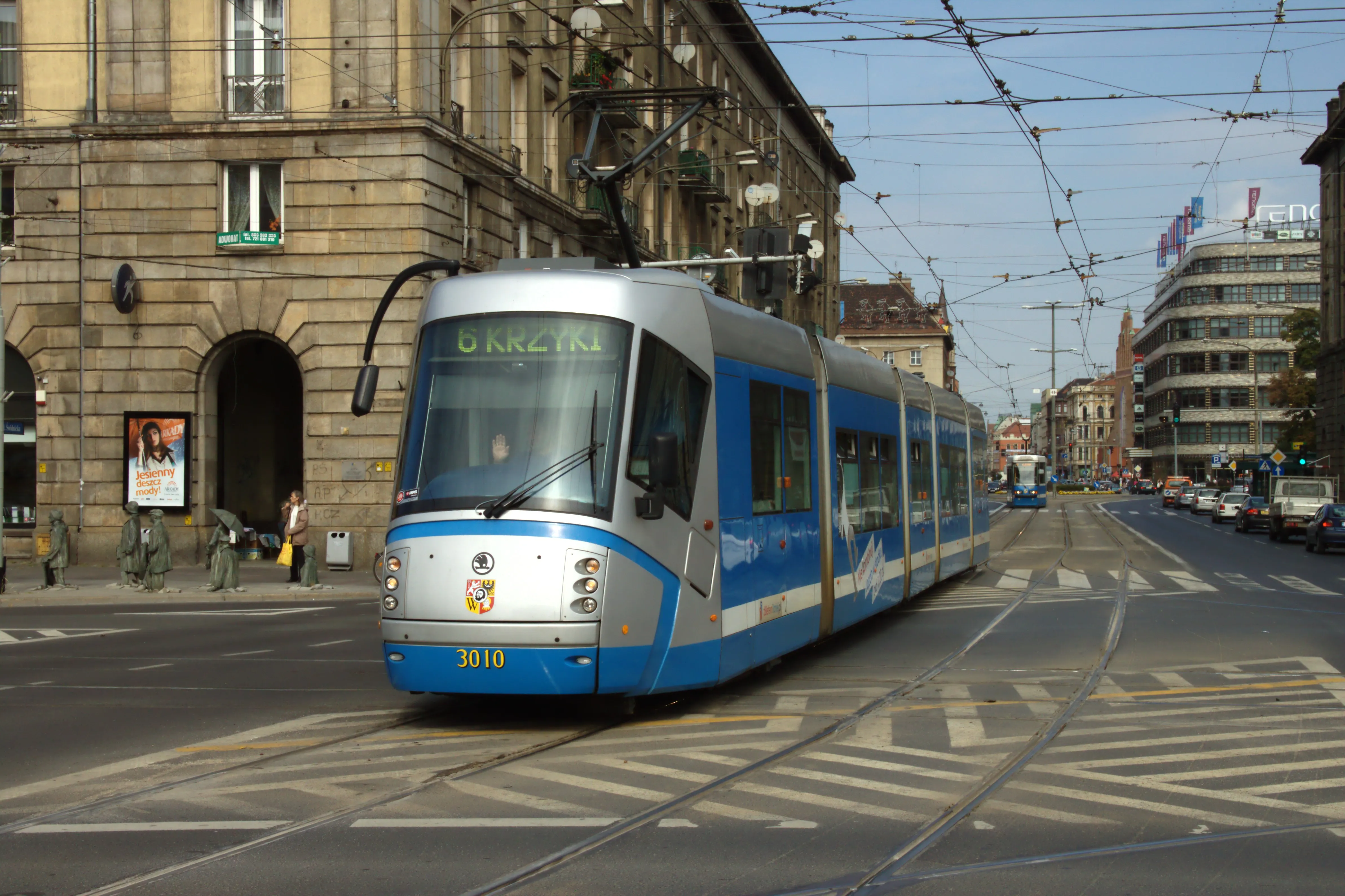 Niebiesko-srebrny tramwaj Škoda 16T na ul. Świdnickiej, na tle kamienic i Renomy.